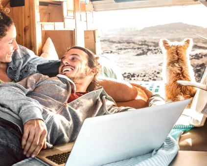 Happy young couple relaxing in their campervan with their dog at the beach.