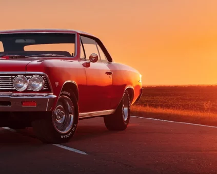 Red SS Classic Car parked in middle of road at sunset