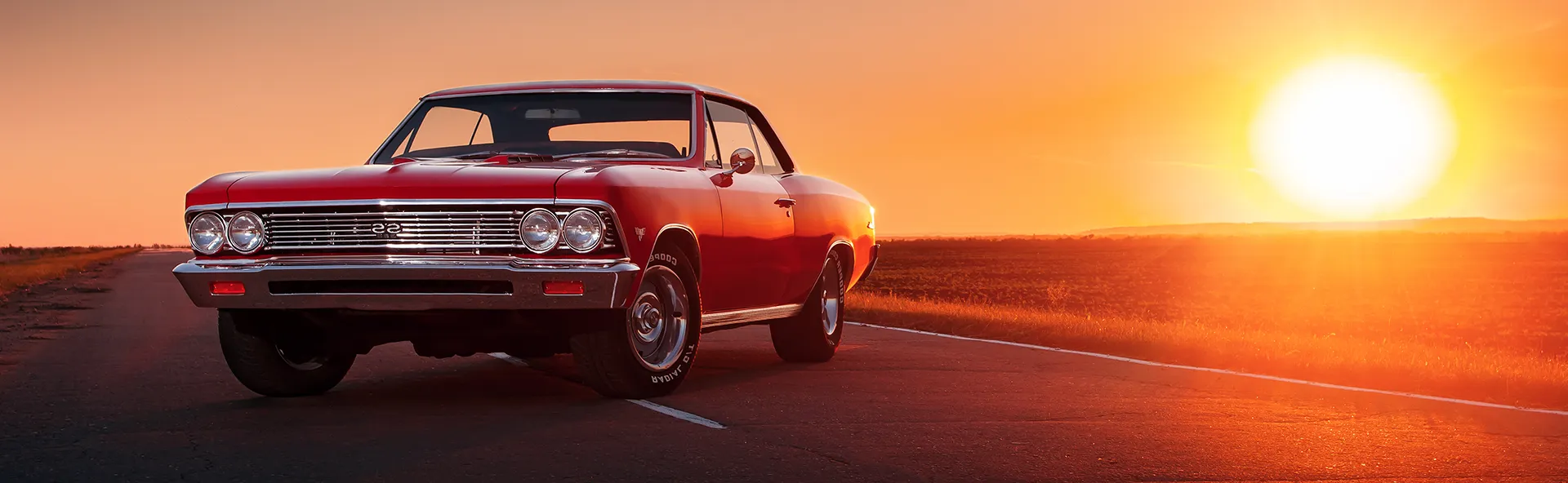 Red SS Classic Car parked in middle of road at sunset