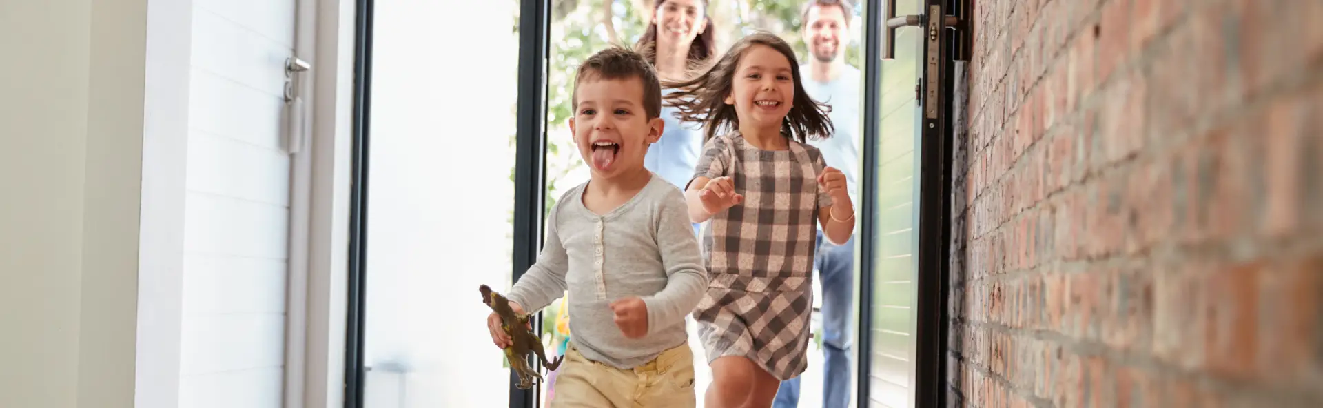 Kids excitedly running into house with parents happily walking behind