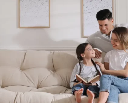 Mother, Father and daughter reading together on couch