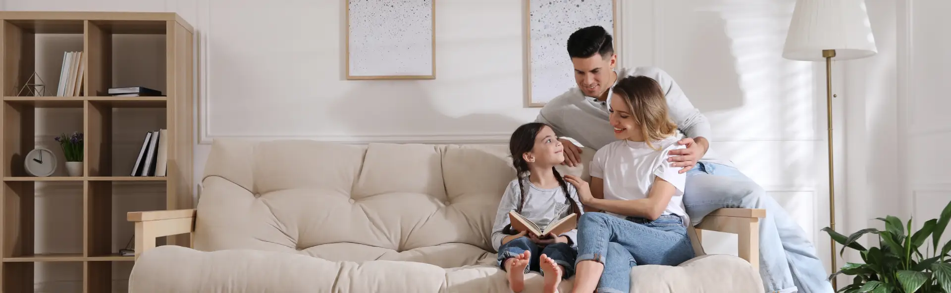 Mother, Father and daughter reading together on couch