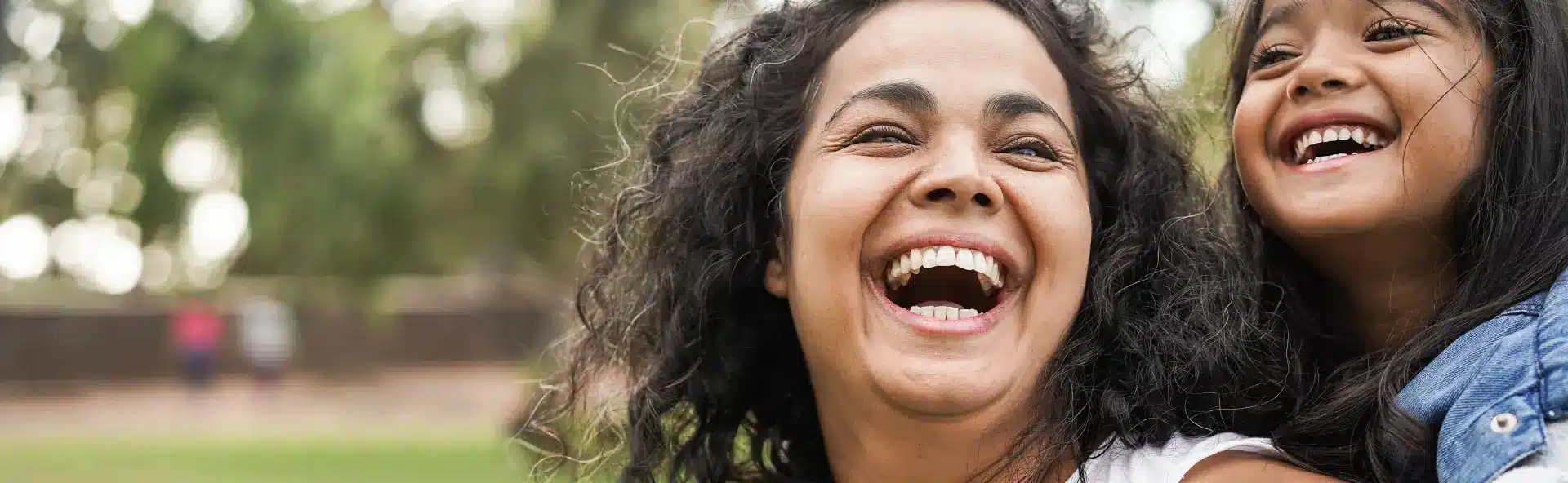 Mother and daughter laughing whilst playing outside