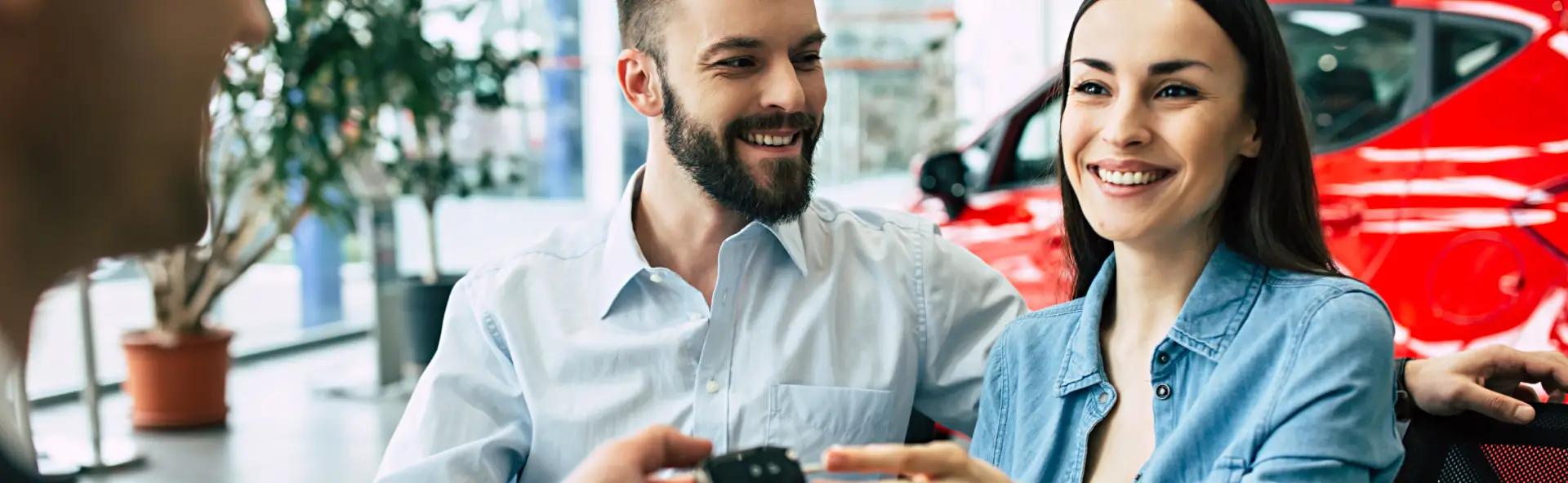 Happy couple accepting the keys to their newly financed car