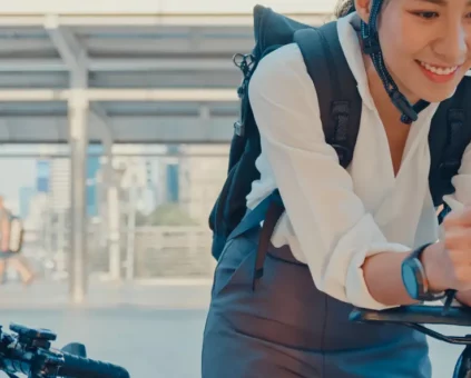 Happy woman riding her bike to work, checking her phone