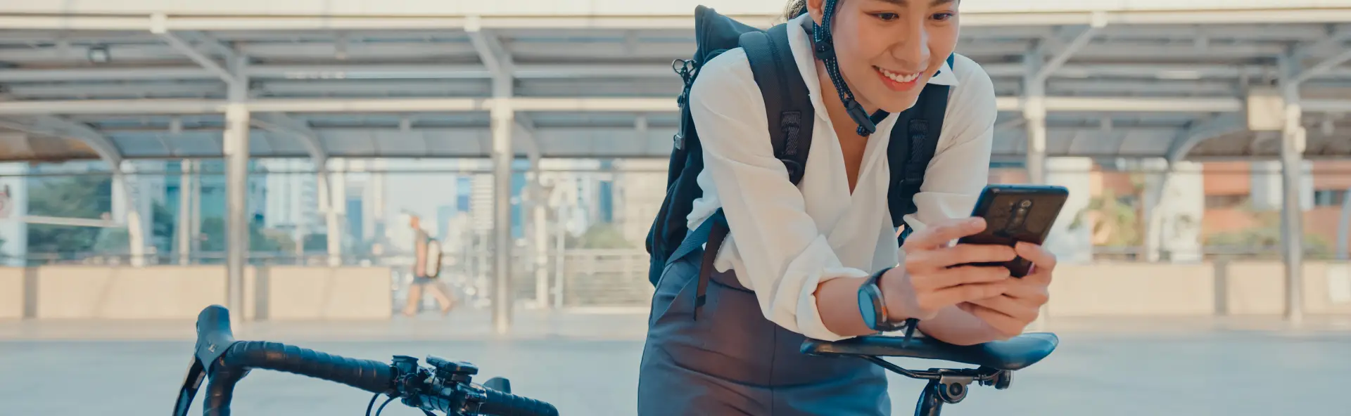 Happy woman riding her bike to work, checking her phone