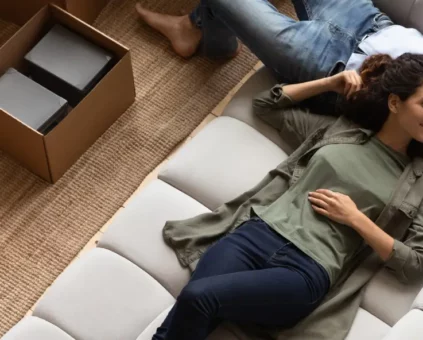 Happy couple relaxing on couch during moving their furniture into the new home