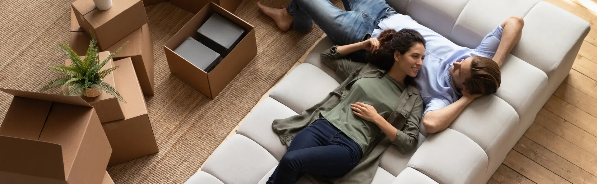 Happy couple relaxing on couch during moving their furniture into the new home