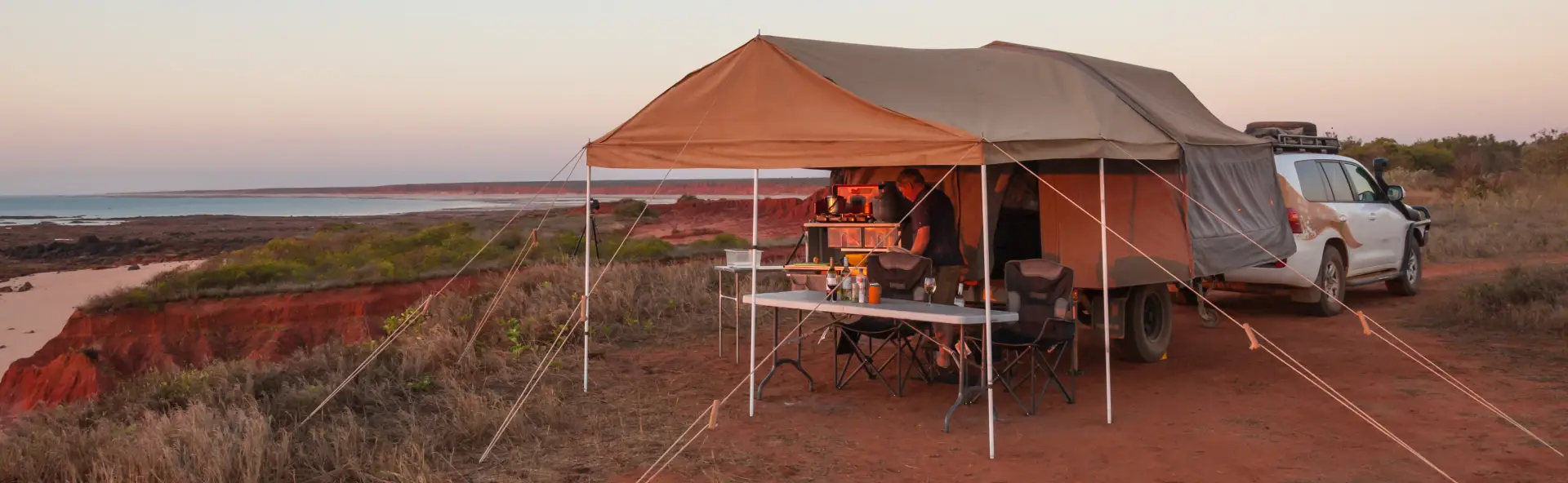 Camper trailer set up behind 4WD at sunset