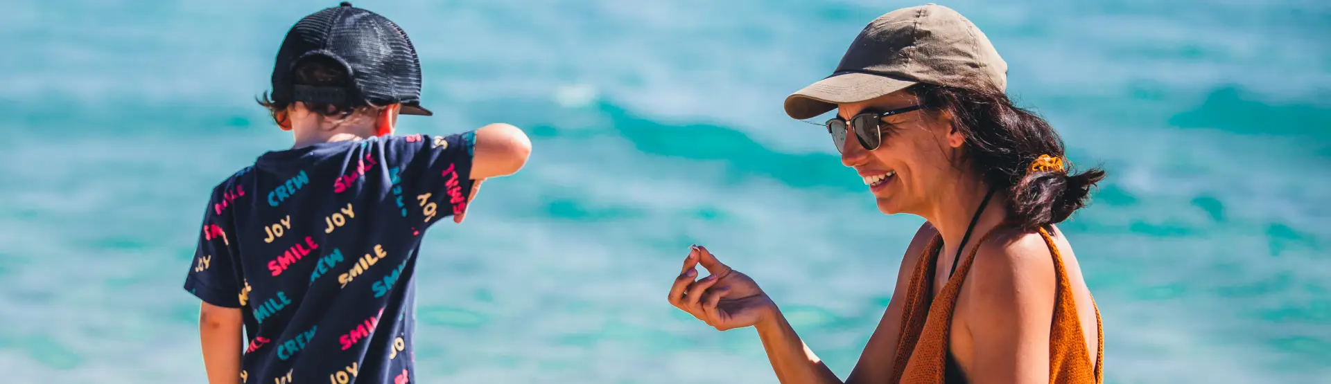 Mum and son playing on the beach with shells