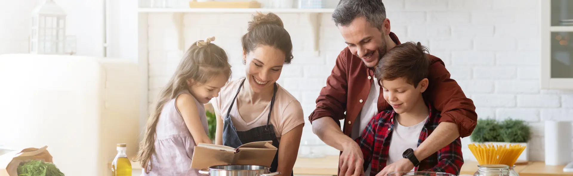 Mother, father, daughter and son cooking together as a family in the kitchen