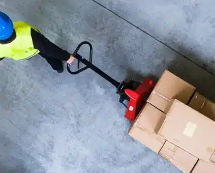 Person Transporting Pallet with Boxes in Warehouse