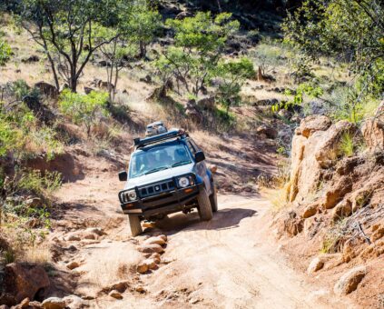 An older 4WD vehicle driving over uneven Australian terrain.