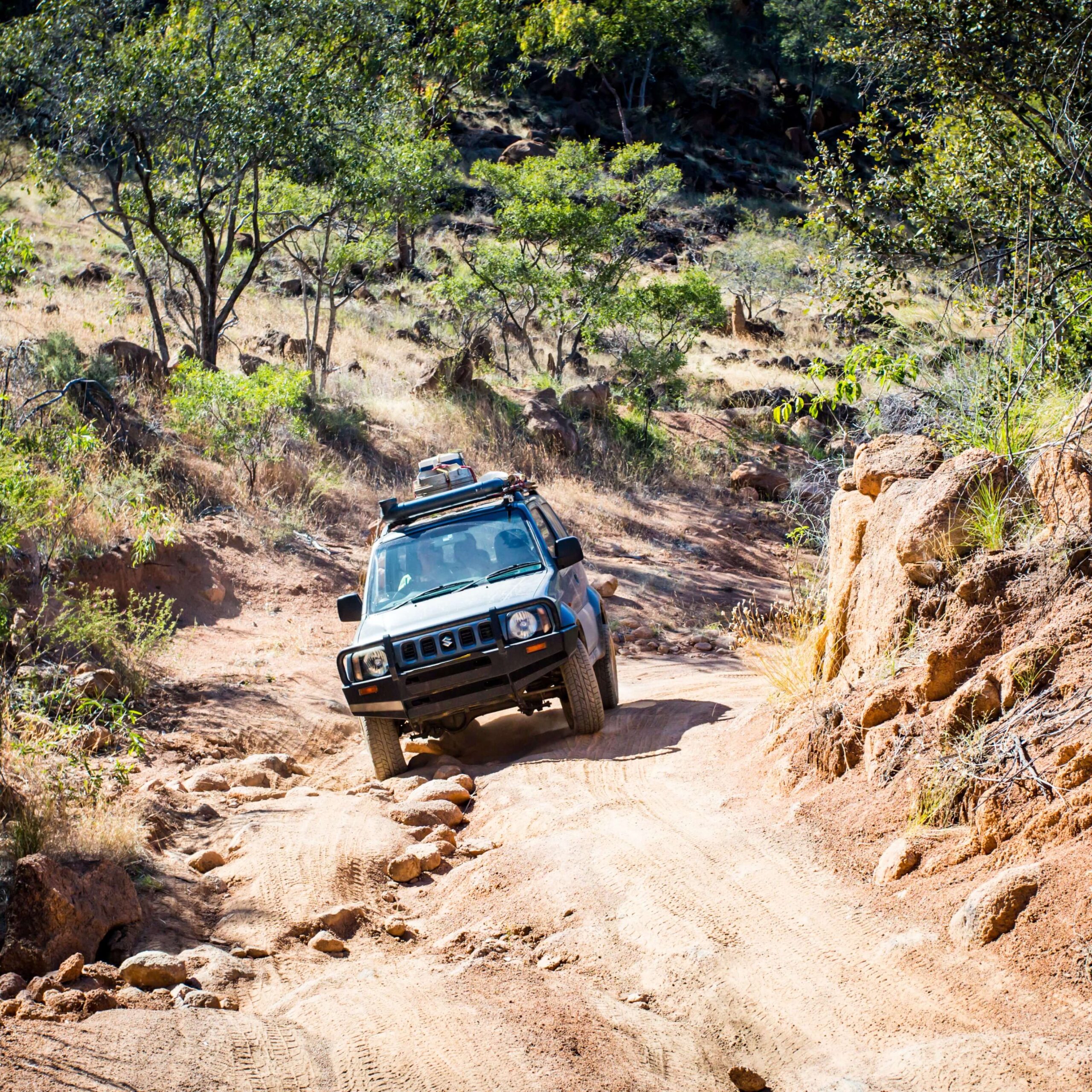 An older 4WD vehicle driving over uneven Australian terrain.