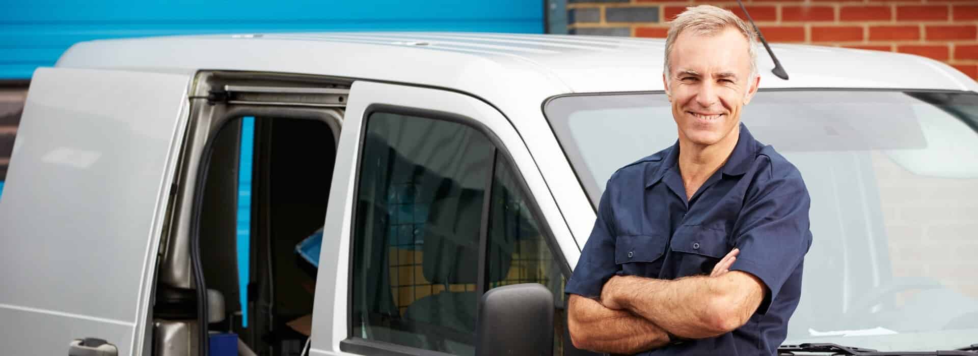 A self-employed painter standing in front of his van filled with equipment.