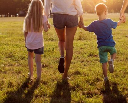 A family holding hands walking into the sunshine.