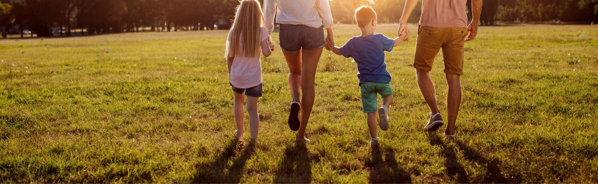 A family holding hands walking into the sunshine.