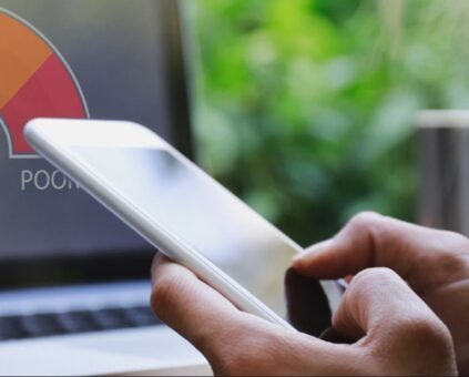 The image shows a hand holding a smartphone with a colorful credit score gauge icon displayed above it, suggesting mobile credit monitoring.