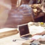 Man reviews plans at workshop bench with laptop and tools. Links to low doc car loans and a simple path for business finance.