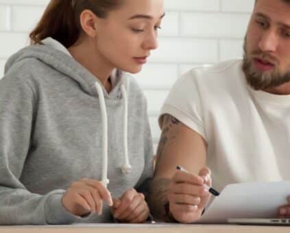 Couple sitting at their table reviewing their debt, with their computer in front of them going to apply for a debt consolidation loan