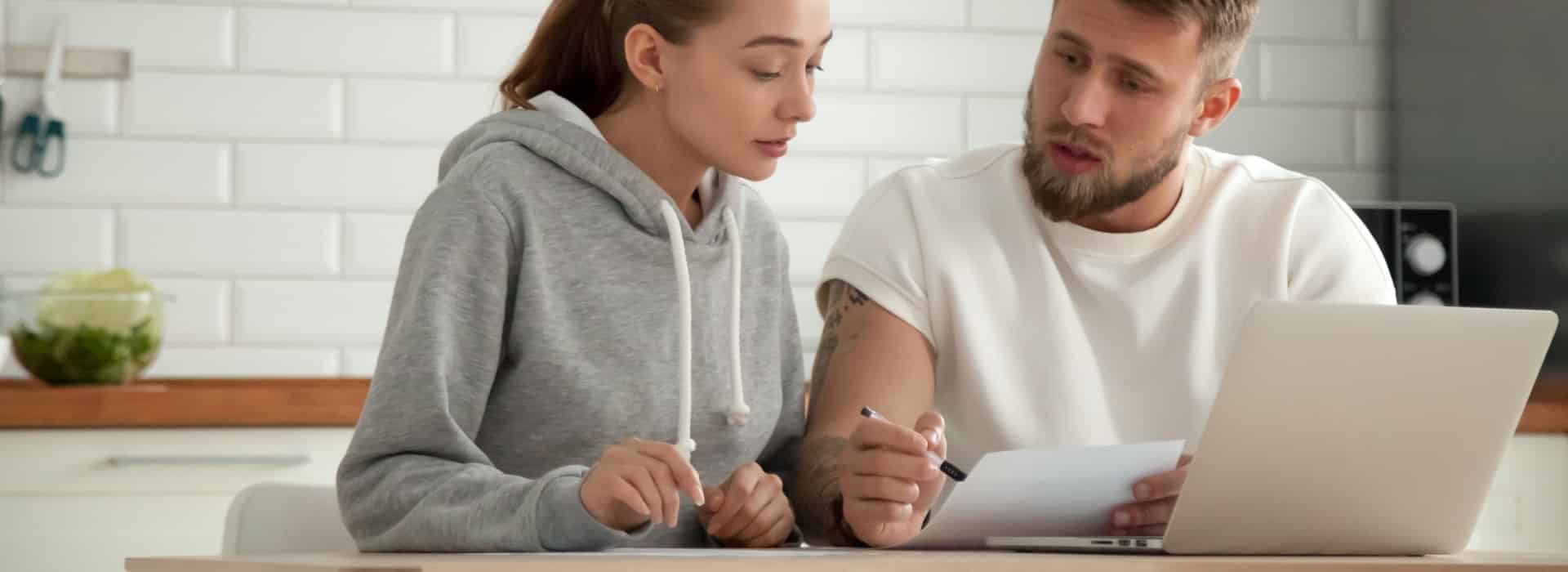 Couple sitting at their table reviewing their debt, with their computer in front of them going to apply for a debt consolidation loan