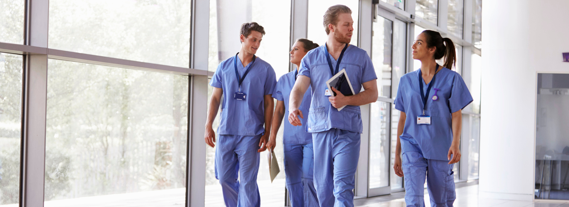 Group of healthcare professionals in scrubs walking through hospital corridor, representing nurses and doctors who can access specialised loan assistance