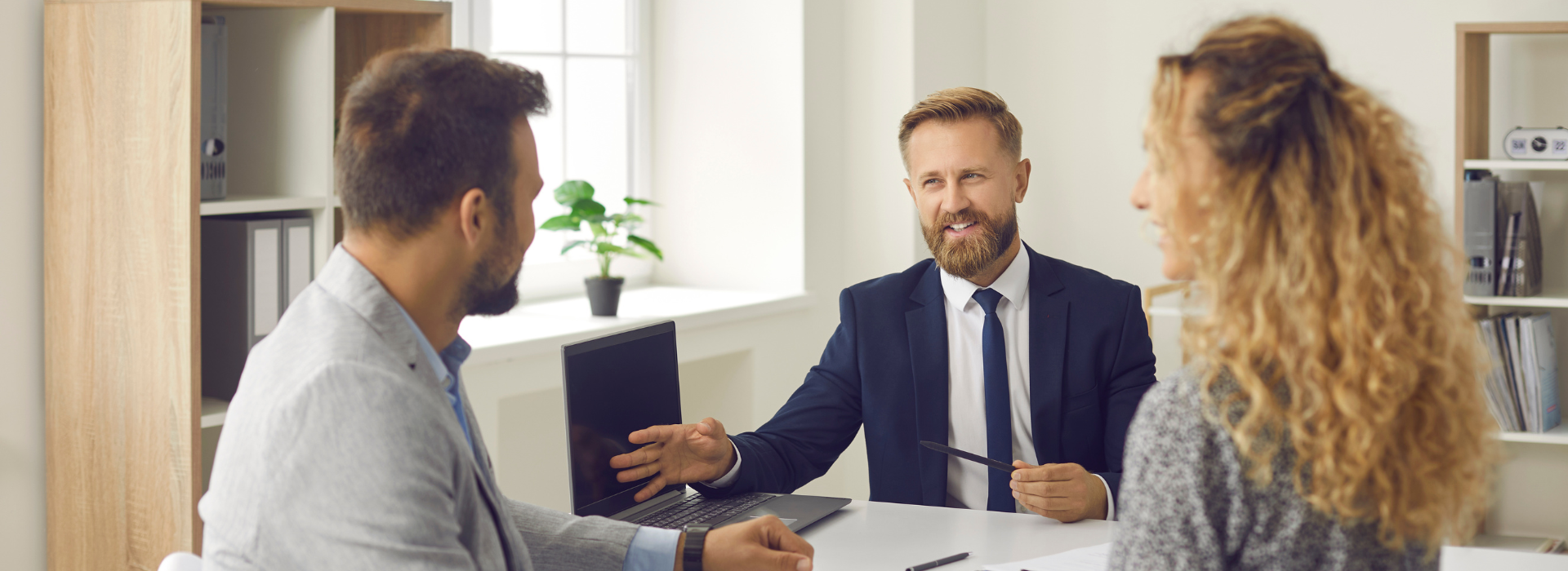 Broker in office consulting with couple at office desk, providing personalised loan guidance and financial solutions