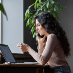 Woman discussing personal loan options on phone while reviewing information on laptop