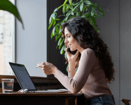 Woman discussing personal loan options on phone while reviewing information on laptop