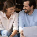Happy couple reviewing debt consolidation loan approval documents at home