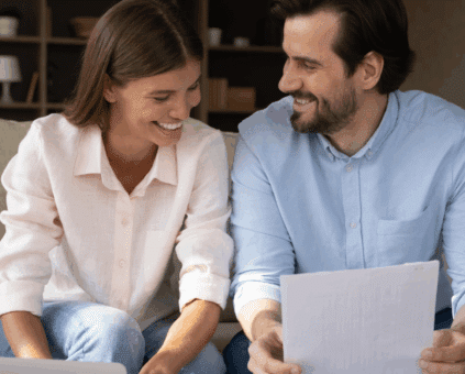 Happy couple reviewing debt consolidation loan approval documents at home