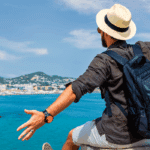 A traveler with a backpack and hat enjoying a scenic coastal view, symbolizing the freedom and experiences made possible through travel loans.