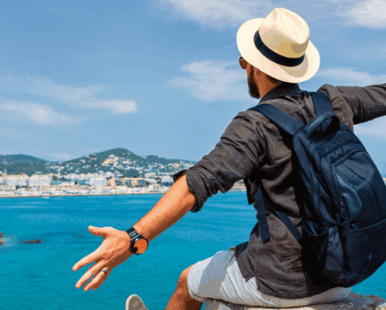 A traveler with a backpack and hat enjoying a scenic coastal view, symbolizing the freedom and experiences made possible through travel loans.