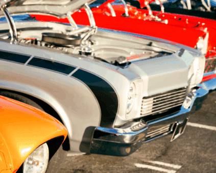 A row of vibrant classic cars with open hoods displayed at a car show, symbolizing the passion and investment behind owning vintage vehicles, highlighting classic car loan options.