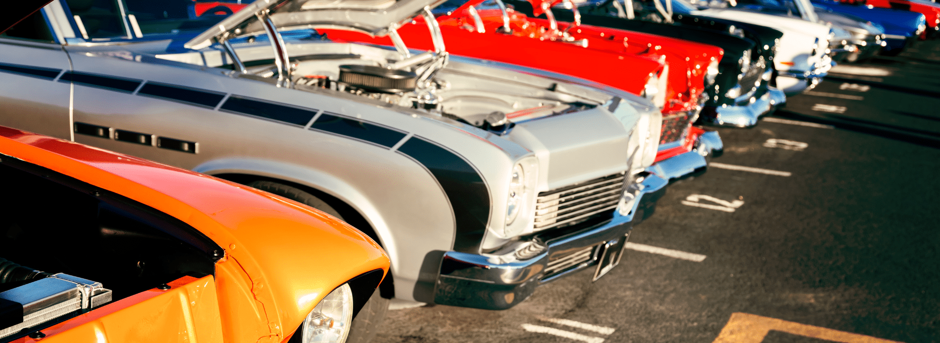A row of vibrant classic cars with open hoods displayed at a car show, symbolizing the passion and investment behind owning vintage vehicles, highlighting classic car loan options.