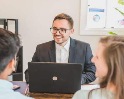 couple sitting with a Fox Finance Group lending specialist, looking relaxed while reviewing car finance options on a laptop