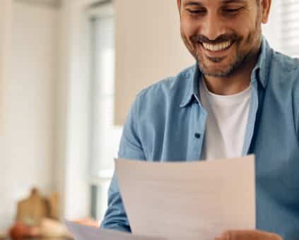 Australian at a kitchen table reviewing loan statements on a laptop, relaxed